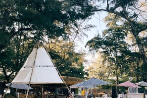 A tented outdoor area with tables and chairs, surrounded by trees. - Here Nashan Nahai Surfing Seaview Homestay (Sanya Wuzhizhou Island Houhai Bay Branch) (Sanya)