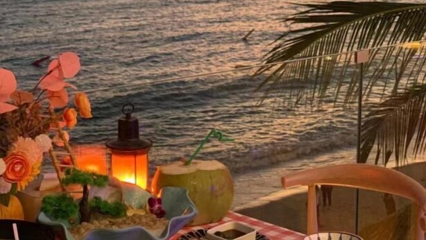 A beach scene with a table set up with a lantern, a pumpkin, and a chair. - Here Nashan Nahai Surfing Seaview Homestay (Sanya Wuzhizhou Island Houhai Bay Branch) (Sanya)