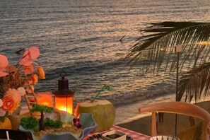 Escena de playa con una mesa decorada con un farolillo, una calabaza y una silla.
