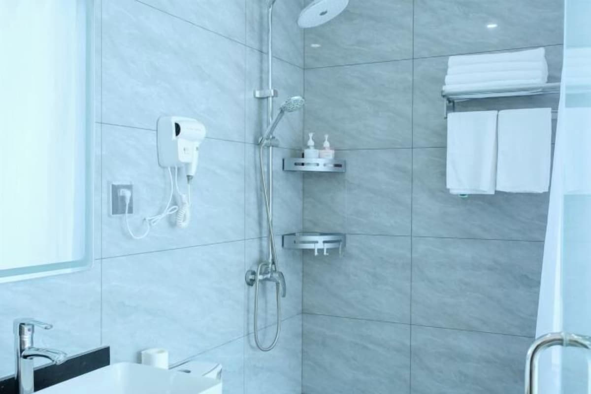 Uma casa de banho moderna com chuveiro, secador de mãos e um porta-toalhas.