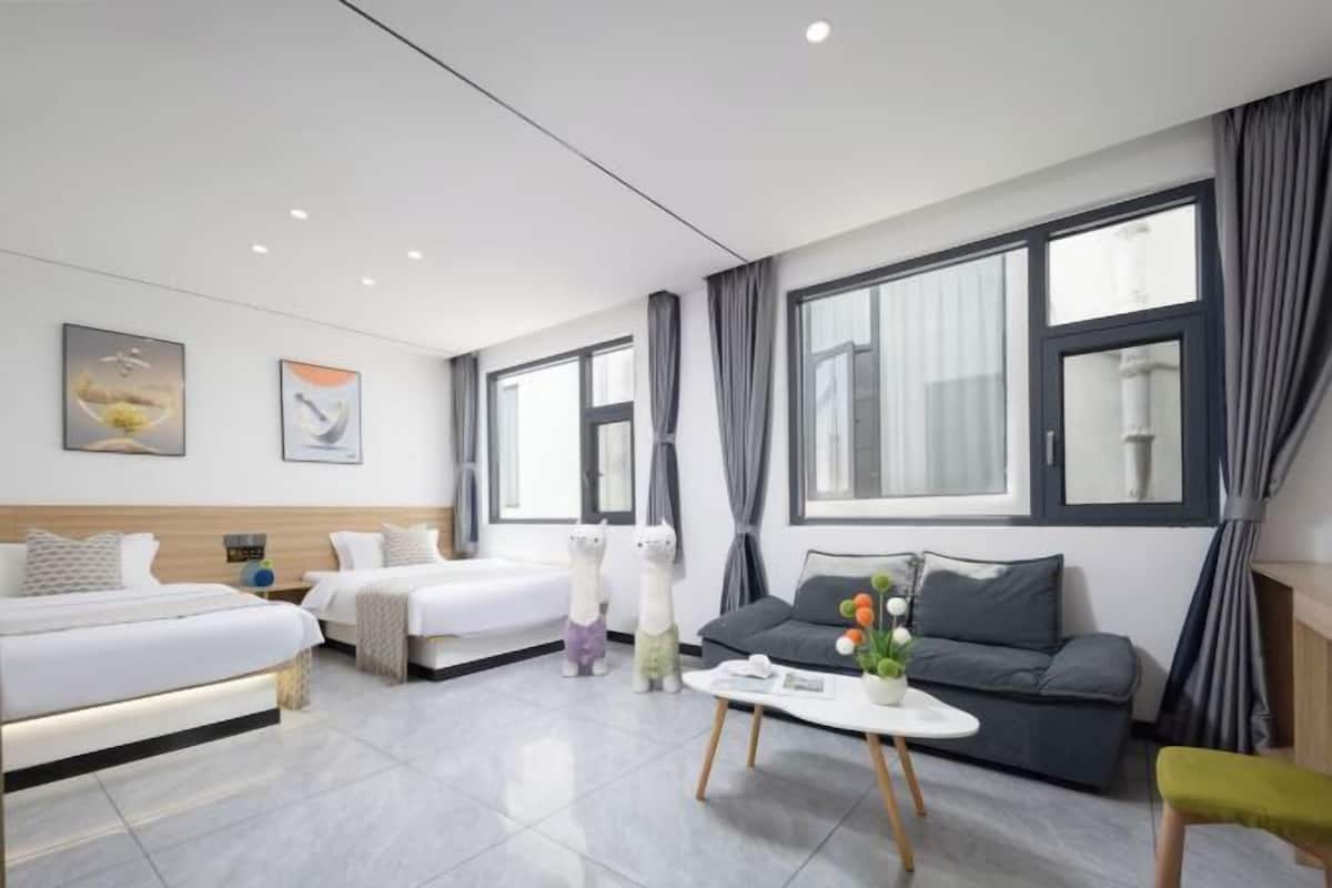 Une chambre d’hôtel moderne avec deux lits, un canapé et une table basse.