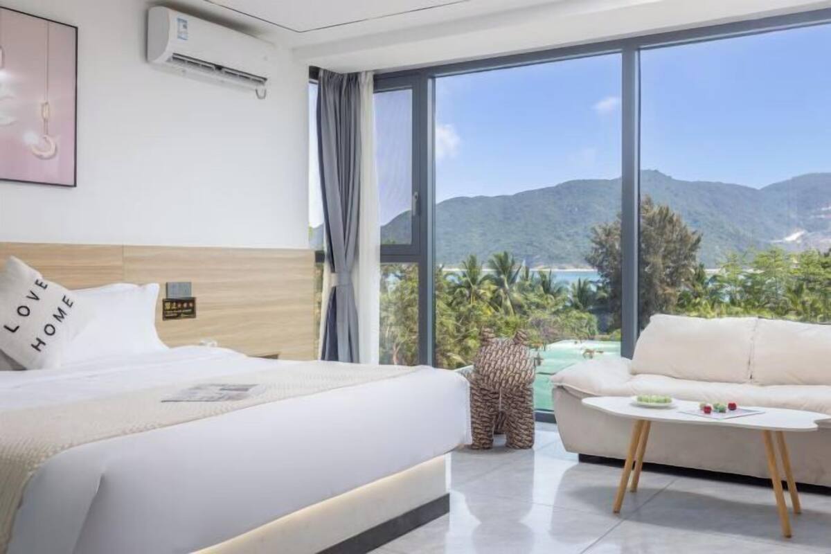 Une chambre d’hôtel comprenant un lit, un canapé, une petite table et une grande fenêtre donnant sur les montagnes et une piscine.