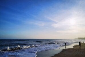 A beach with waves, a clear sky, and a distant mountain. - Here Nashan Nahai Surfing Seaview Homestay (Sanya Wuzhizhou Island Houhai Bay Branch) (Sanya)