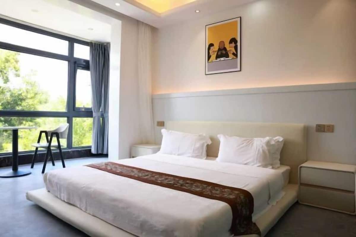 Une chambre d’hôtel moderne avec un grand lit, une table à manger et une fenêtre avec des rideaux.