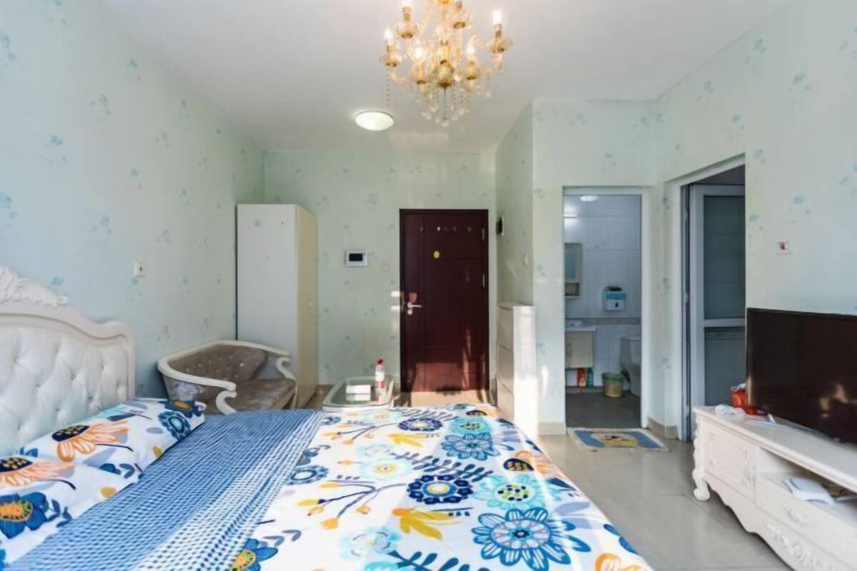 Ein Schlafzimmer mit Bett, Sessel, Fernseher und Kleiderschrank.