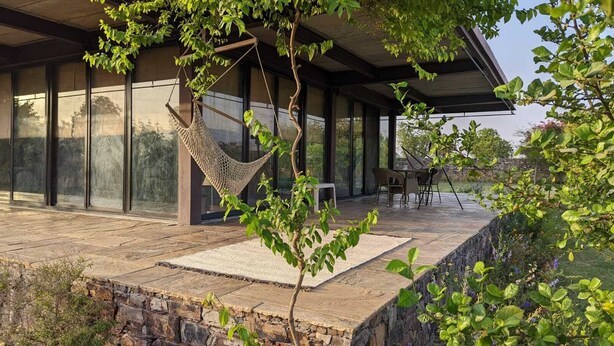 Un espace extérieur abrité, doté d’un hamac, d’un sol en pierre et d’un coin salon avec des chaises.