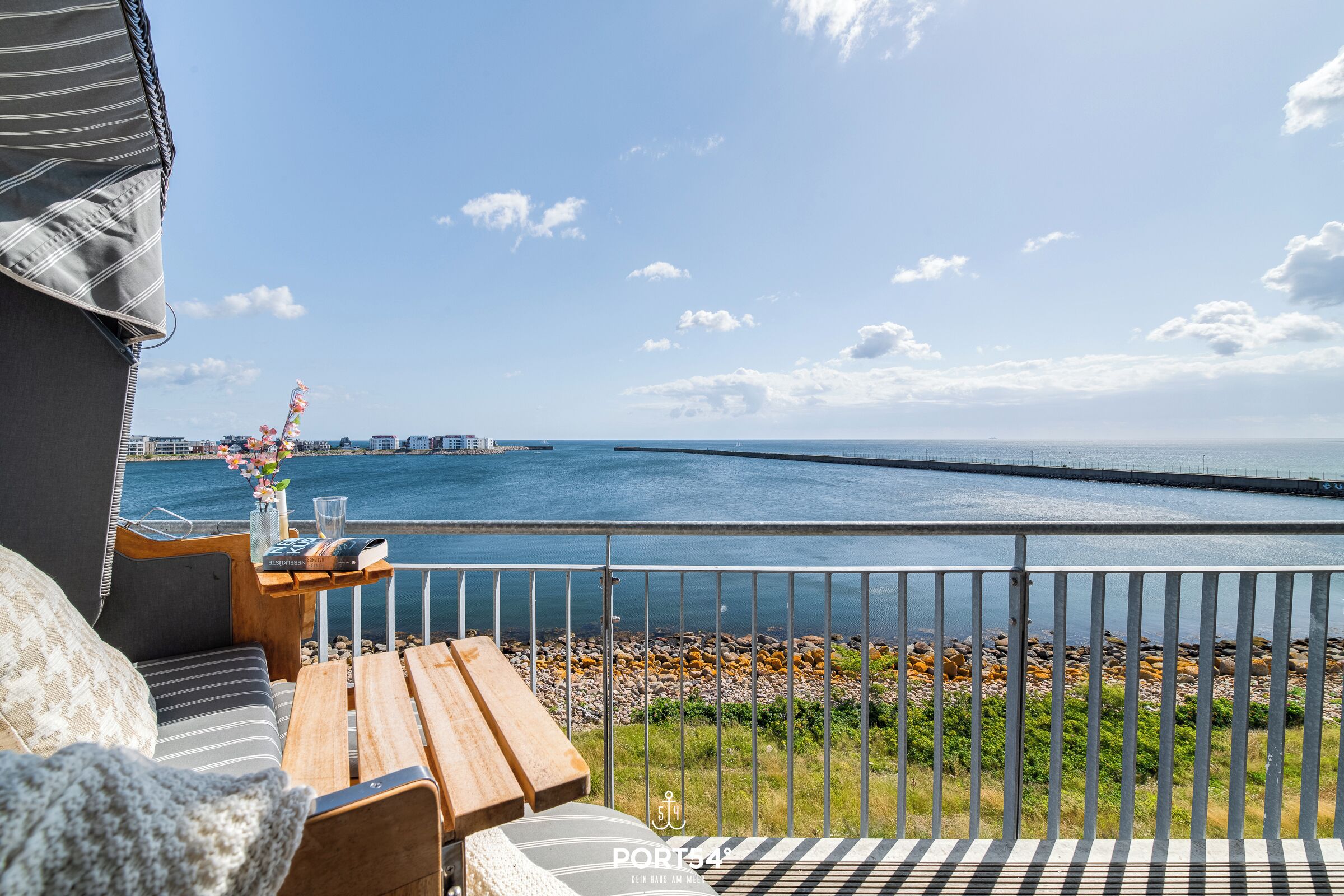 En balkong med utsikt över havet, ett träbord och en soffa.