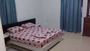 Une chambre à coucher avec un lit, des rideaux, une commode et une table de chevet.