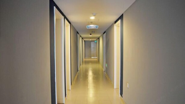 Un pasillo largo y estrecho con puertas a ambos lados, que conduce a habitaciones.