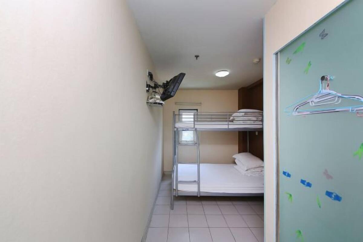 A bunk bed room with a small desk and a mirror.