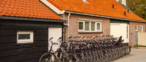 A row of bicycles parked outside a building with a red-tiled roof.