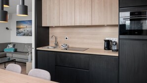 Een moderne keuken met een houten aanrechtblad, zwarte kastjes en een inbouwoven.