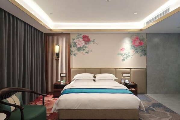 A hotel room with a bed, a chair, a nightstand, a lamp, and a floral wall mural. - Mudan Hotel (Heze)