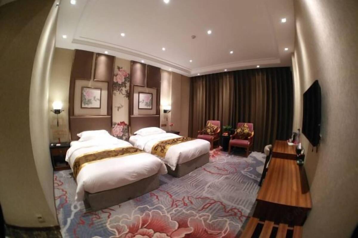 A hotel room with two beds, a desk, and a chair.