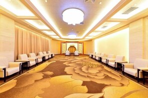 A conference room with a long table, rows of chairs, and a carpeted floor. - Mudan Hotel (Heze)