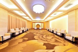 Un salón de conferencias con una larga mesa, filas de sillas y suelo alfombrado.