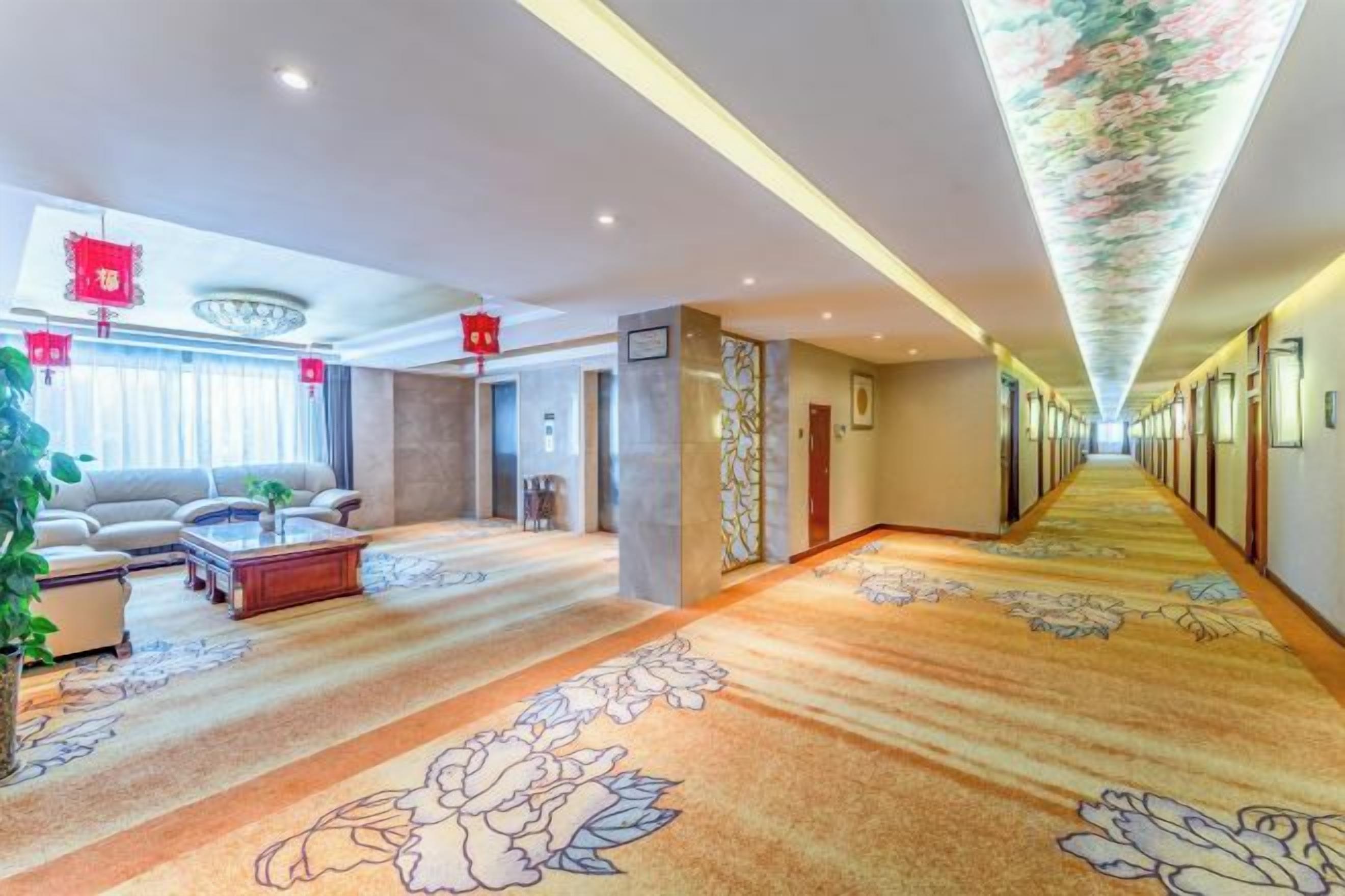 A hotel lobby with a carpeted floor, a sofa, a coffee table, and a plant.