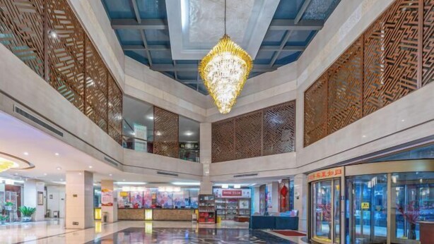 Ein geräumiger Atrium mit hoher Decke, einem zentralen Chandelier und einem gläsernen Aufzug.