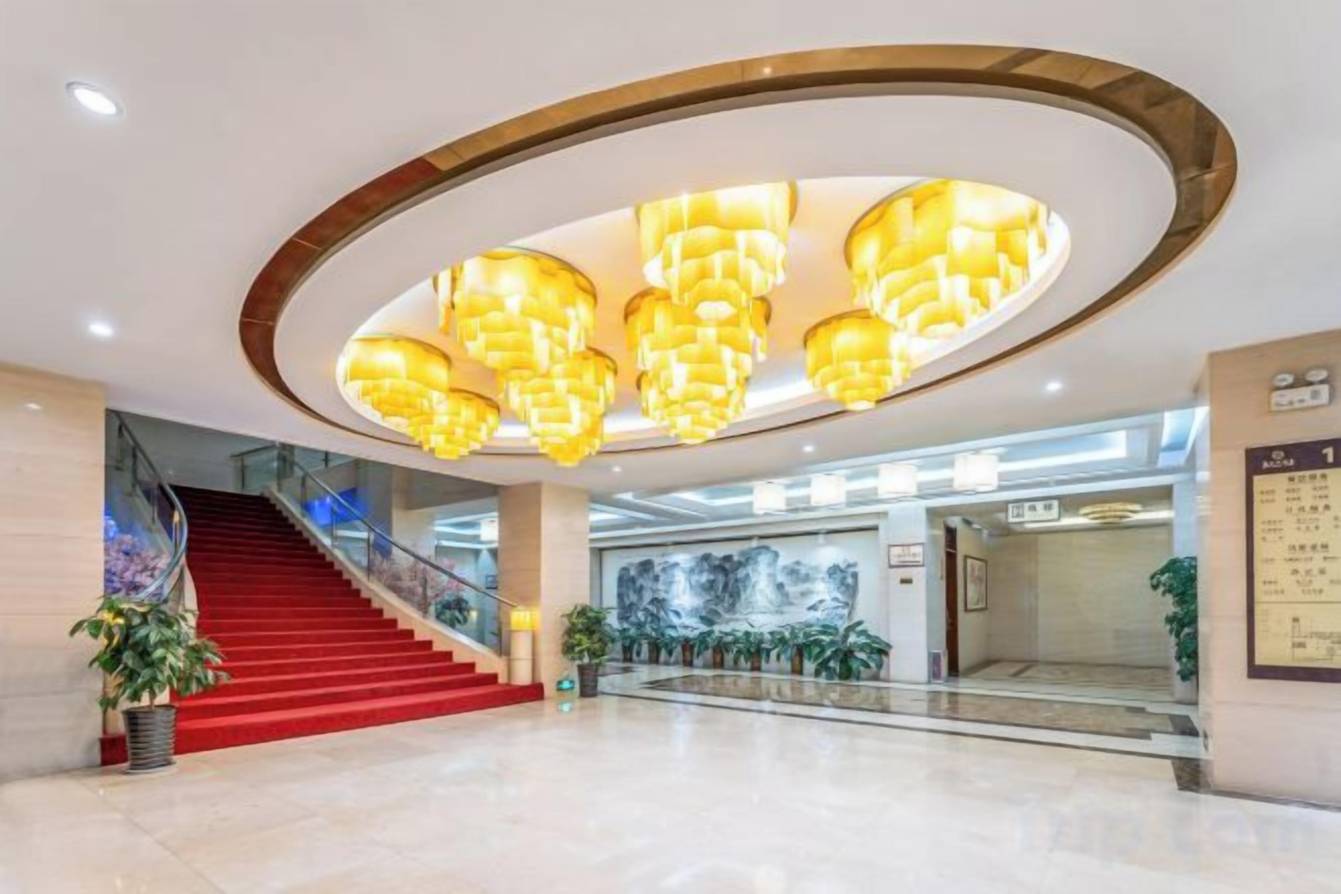 A spacious lobby with a grand staircase, a large chandelier, and a modern design.