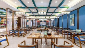 Ein großzügiges Restaurant mit mehreren Tischen und Stühlen, einem modernen Deckenstil und Kunstwerken an den Wänden.