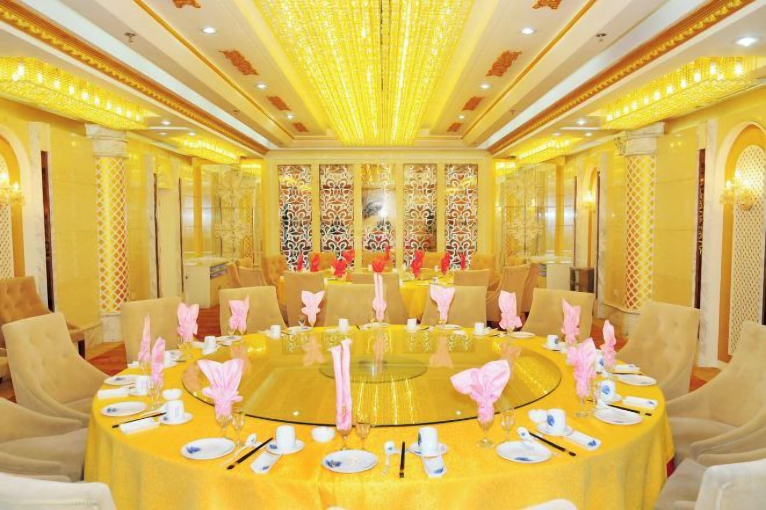Mesa redonda dispuesta para una comida, con sillas alrededor, en una habitación con decoración elaborada y candelabros.