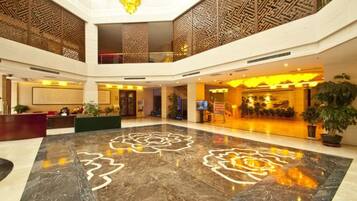 A spacious lobby with a marble floor, a reception desk, and a staircase leading to an upper level.