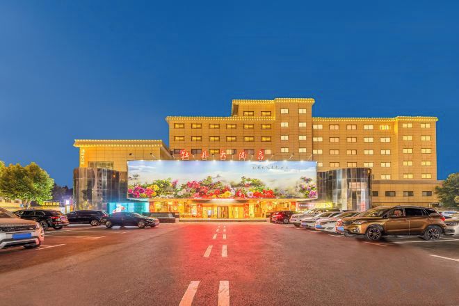 A multi-story hotel with a large entrance and a parking lot in front.
