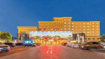 A multi-story hotel with a large entrance and a parking lot in front.