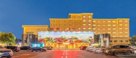 A multi-story hotel with a large entrance and a parking lot in front.