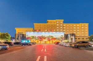Un hotel de varios pisos con una entrada amplia y un estacionamiento frente a él.