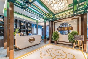 A reception area with a counter, a signboard, and a decorative ceiling. - Mudan Hotel (Heze)
