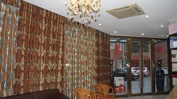 A lobby with a sofa, chairs, a chandelier, and a patterned wall.