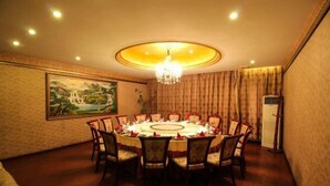 A dining room with a round table, chairs, a chandelier, a painting, and a wall-mounted air conditioner. - Shuyang Sanhe Hotel (Puyang)