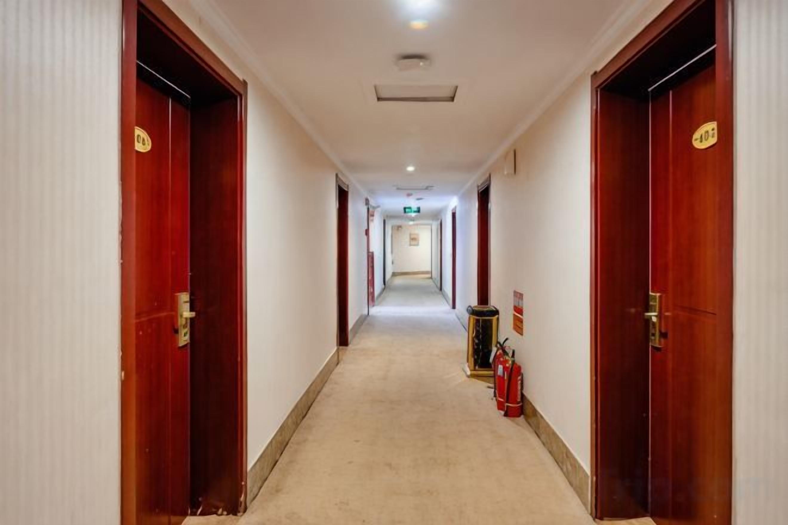 A hotel corridor with wooden doors, a fire extinguisher, and a sign on the wall.