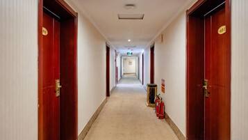 A hotel corridor with wooden doors, a fire extinguisher, and a sign on the wall.
