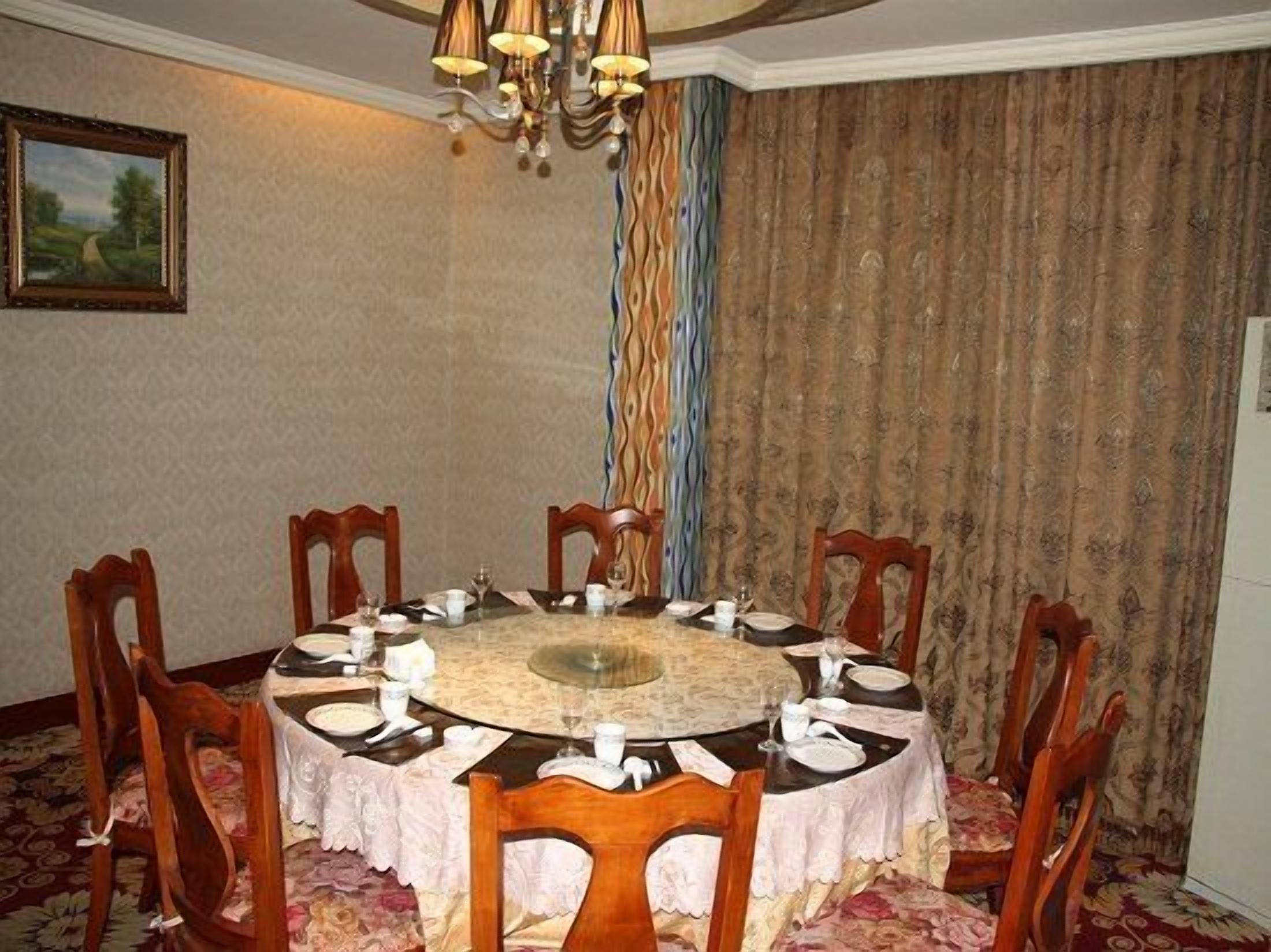 A dining room with a round table set for six, surrounded by wooden chairs.