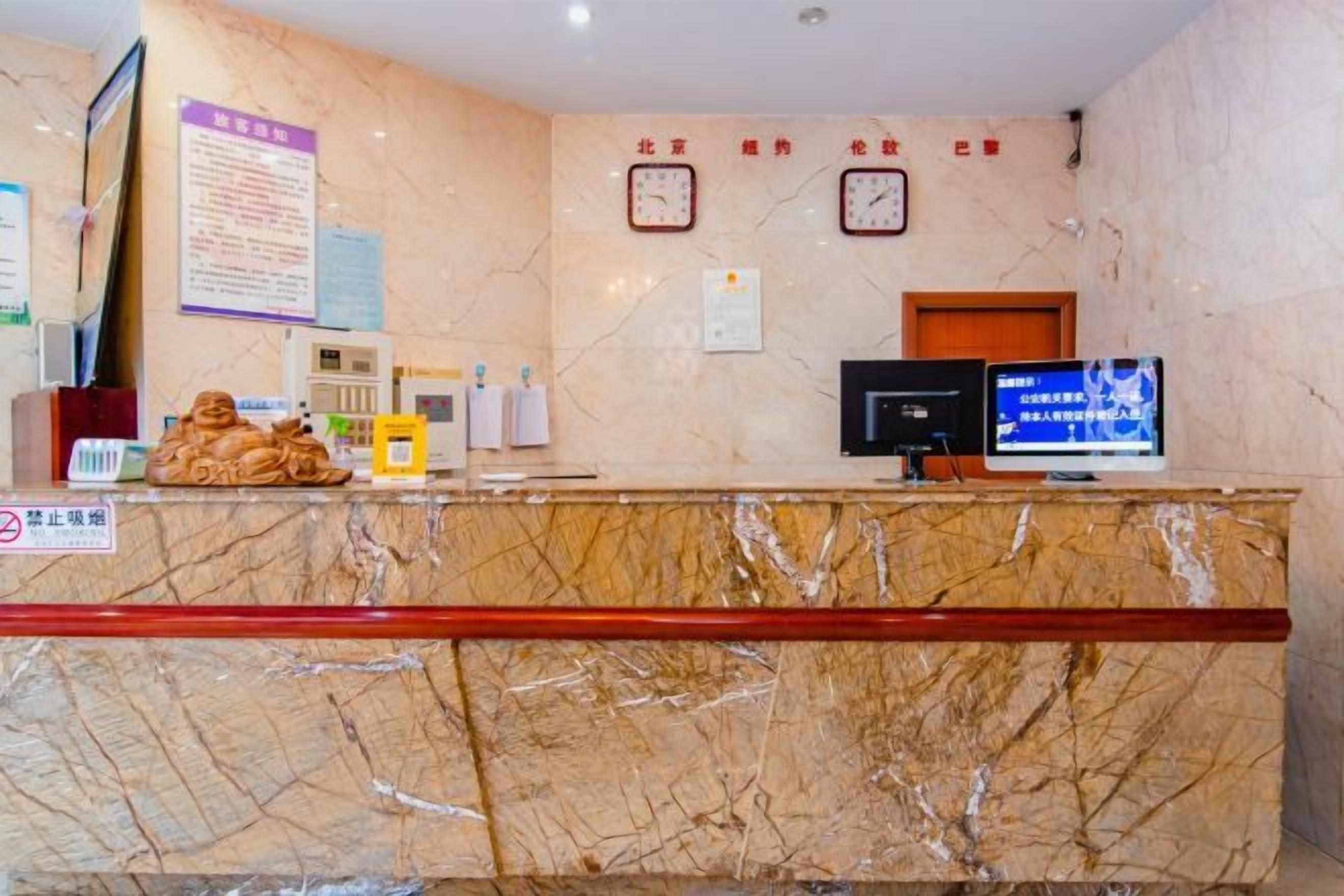 A hotel reception desk with a marble counter, a television, clocks, and a sign indicating no smoking.