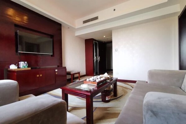 A modern living room with a flat-screen TV, a red cabinet, a coffee table, and a beige sofa. - Shanggao Yingbin Hotel (Shanggao)