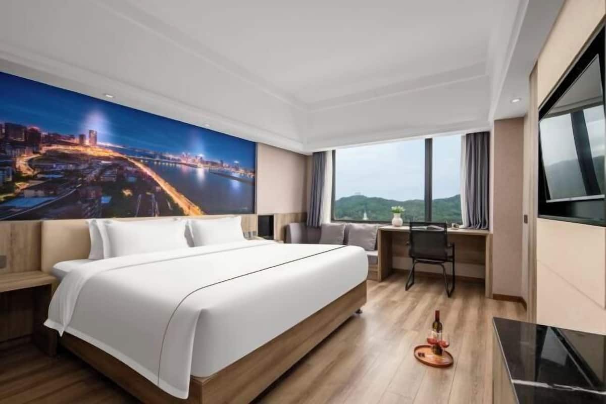 Une chambre d’hôtel avec un grand lit, un bureau, une chaise et un téléviseur.