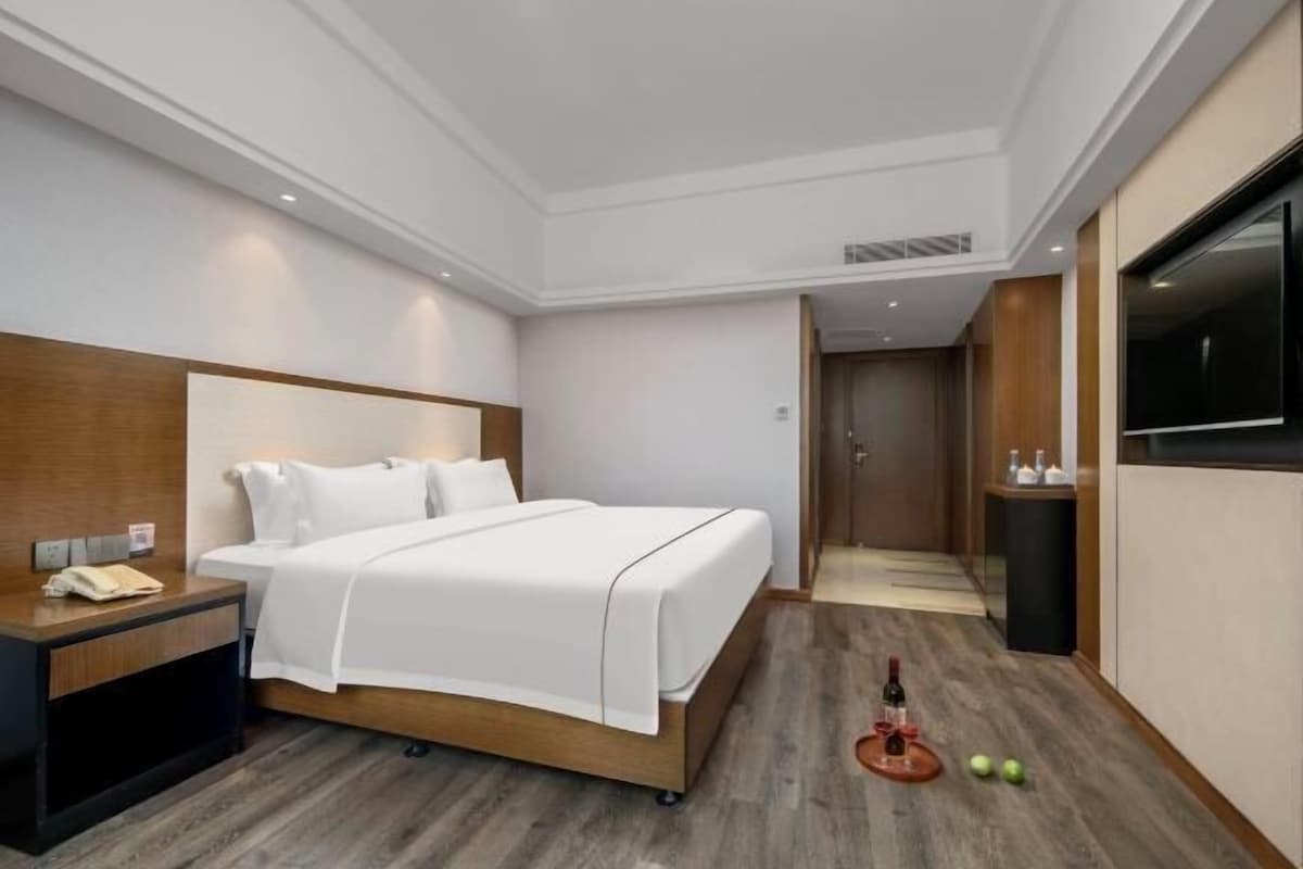 A hotel room with a bed, bedside table, and a minibar.