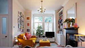 A living room with a sofa, a television, a fireplace, and a bookshelf. - Thames-side Retreat, by Veeve (London)