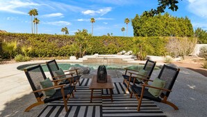 A poolside area with four chairs and a table, surrounded by lush greenery and palm trees. - Newly renovated 4-bedroom house with pool and two main suites in Palm Springs.  (Palm Springs)