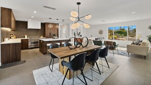 A modern kitchen with a central island, black chairs, and a wooden dining table. - Newly renovated 4-bedroom house with pool and two main suites in Palm Springs.  (Palm Springs)