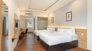 Quarto de hotel com duas camas, uma escrivaninha, uma cadeira e uma televisão.