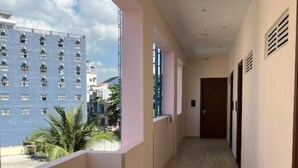 Um corredor com vista para um arranha-céu e palmeiras.