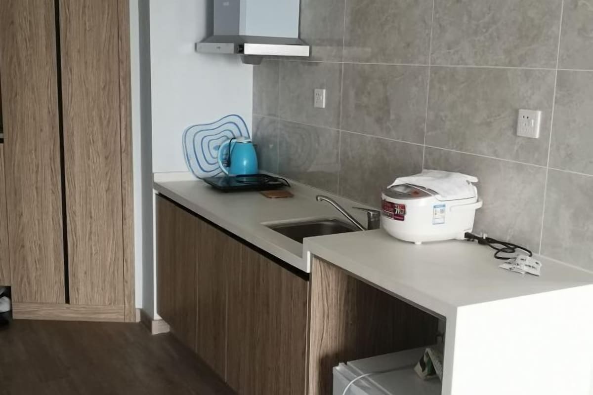 A modern kitchen with a countertop, sink, and a rice cooker.