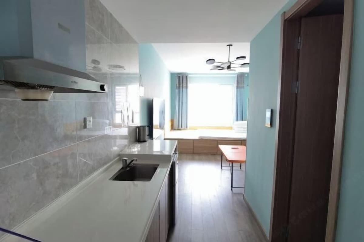 A modern kitchen with a built-in stove, a sink, and a window with curtains.