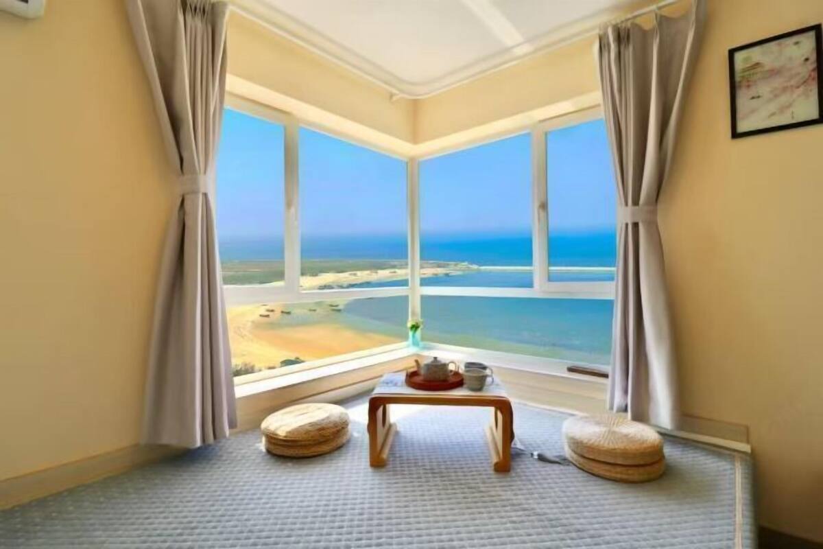 Una habitación con un gran ventanal que ofrece vistas a la playa y al océano.