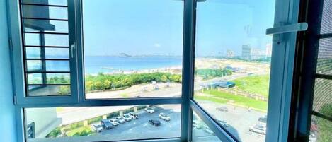 A room with a large window offering a view of a parking lot and a beach.