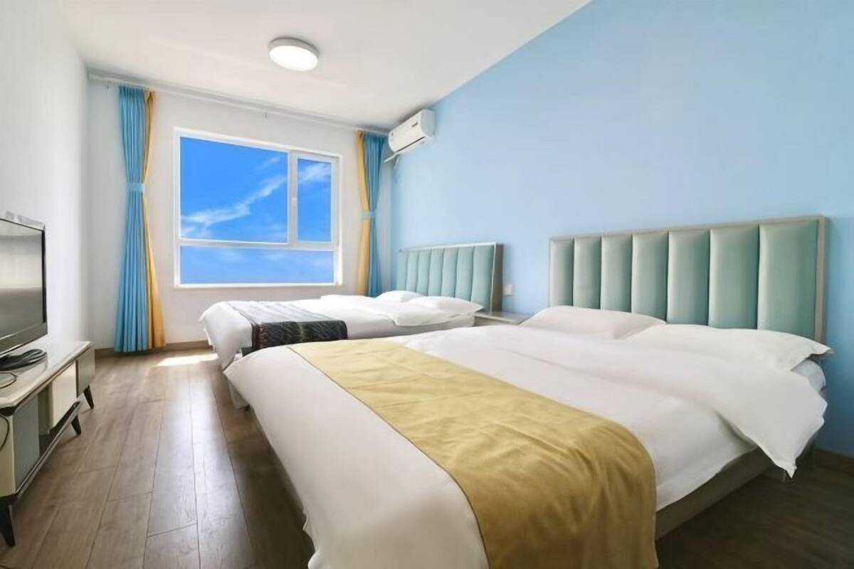 Habitación de hotel con dos camas, un escritorio, un televisor y una ventana con cortinas.